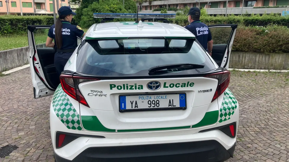 Un'auto e due agenti della Polizia locale - © www.giornaledibrescia.it