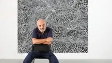 Un ritratto di Maurizio Donzelli davanti ad una sua opera