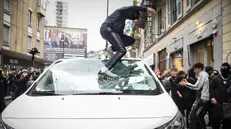 Un ragazzo distrugge un'auto a Milano - Foto Ansa © www.giornaledibrescia.it