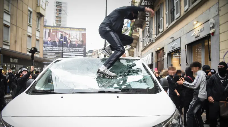 Un ragazzo distrugge un'auto a Milano - Foto Ansa © www.giornaledibrescia.it